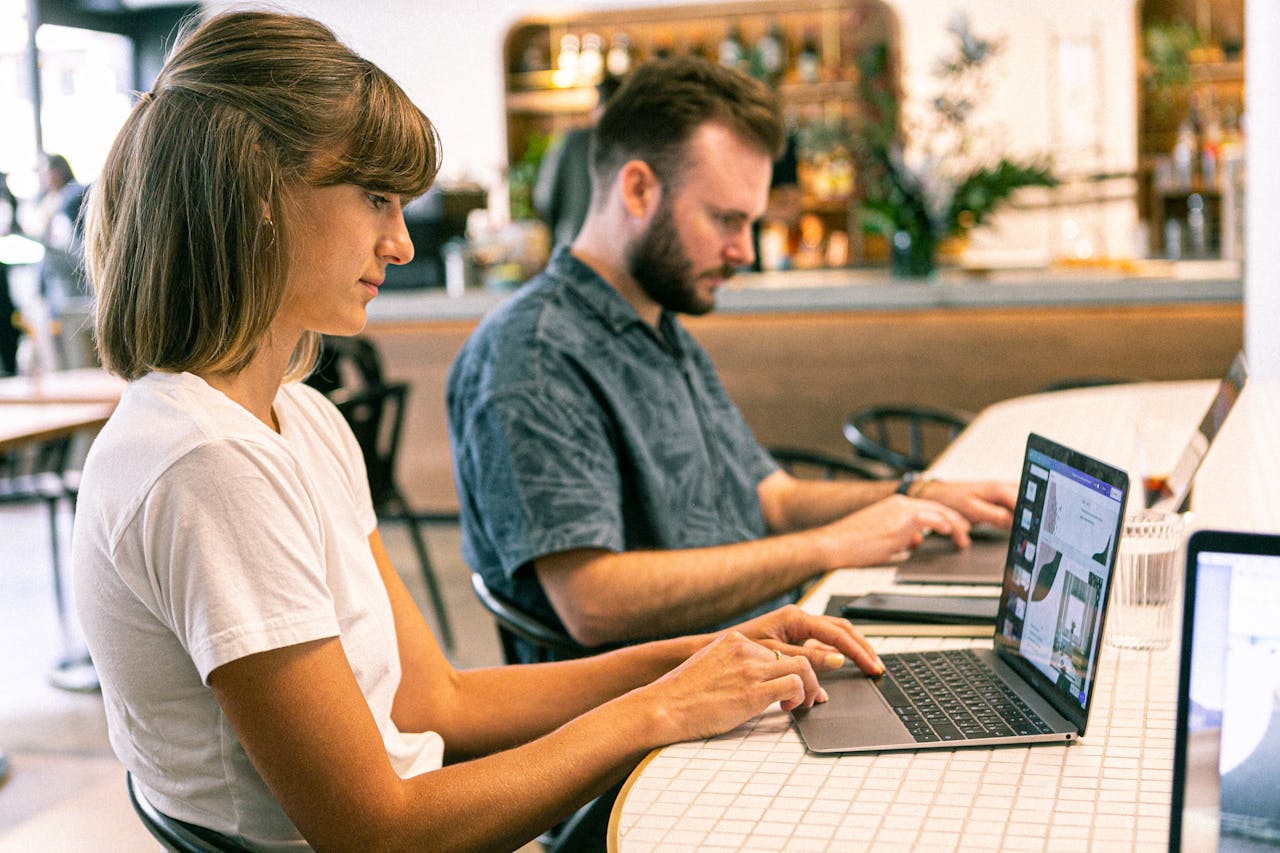 Mastering the First Impression: Your intriguing post title goes here Two young professionals working on laptops in a modern cafe setting.